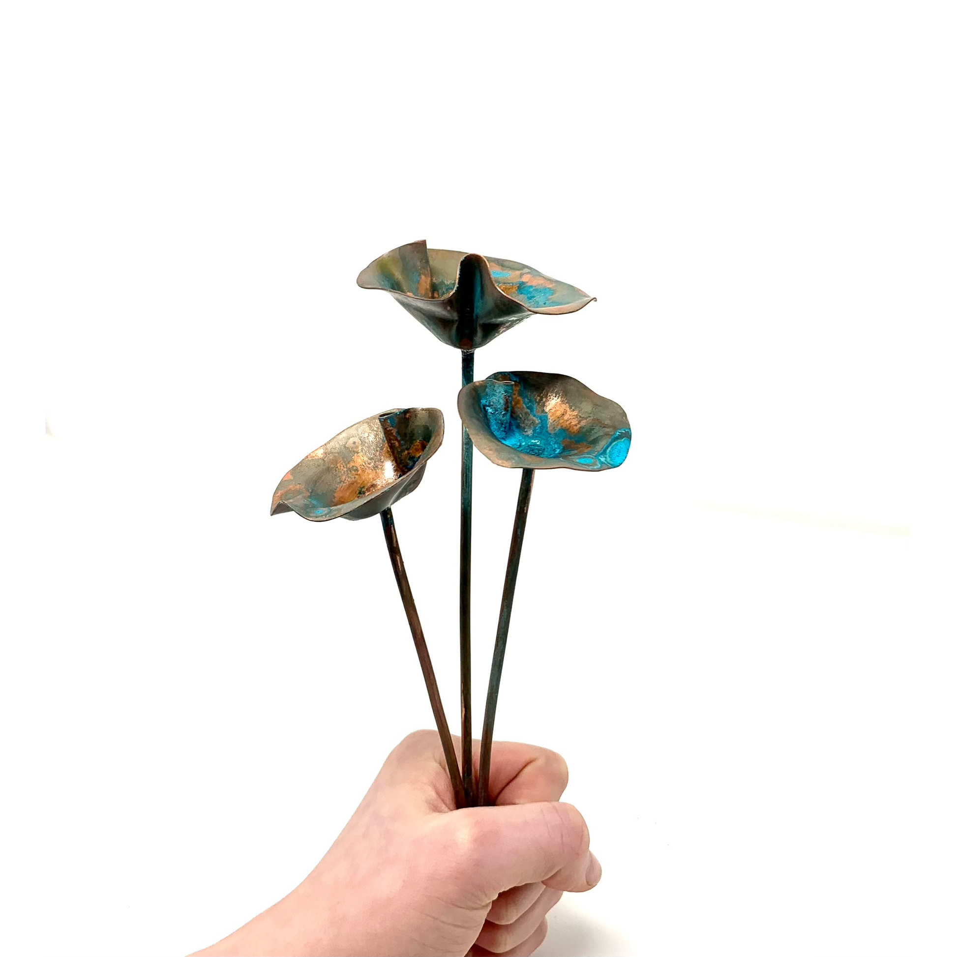 Child's hand holding a bouquet of copper patina flowers